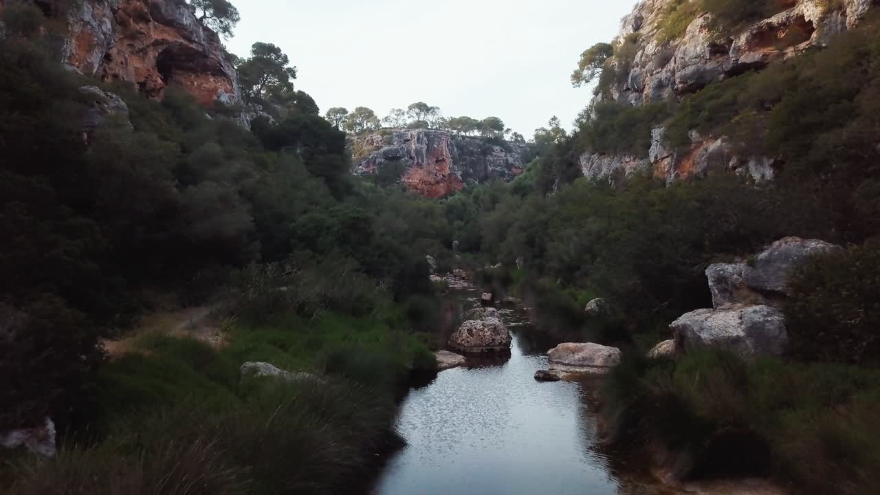 vuelo aéreo fpv sobre el río con rocas en barranco con cielo brillante al atardecer