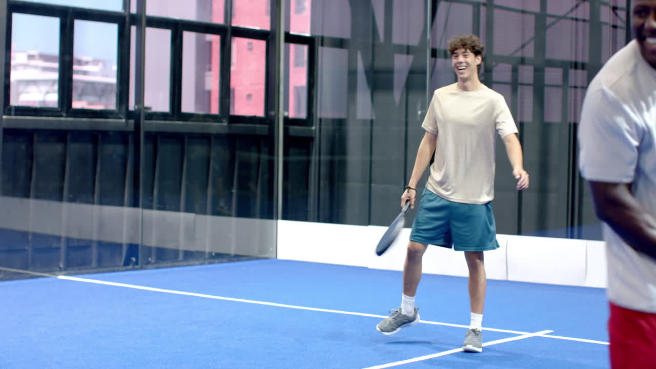 Young man playing padel tennis, focused and ready on indoor court