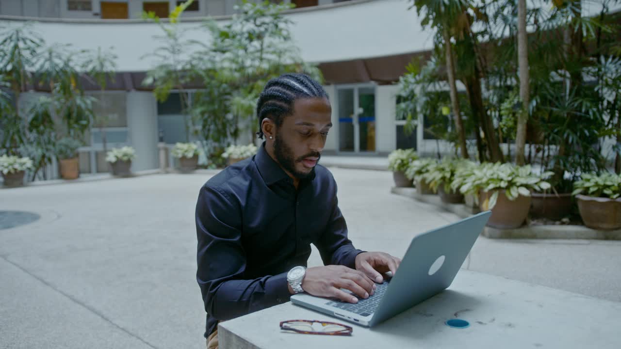 Man working on a laptop in a courtyard