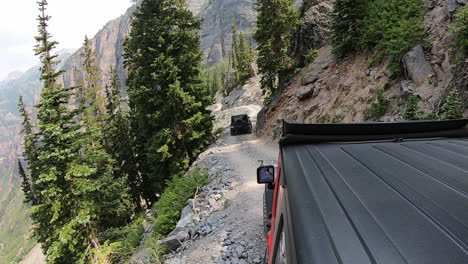 two 4wd vehicles driving on trail cut into mountain side high above yankee boy basin in the san juan mountains near ouray colorado