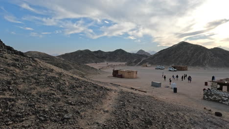 Slow-motion---People-standing-and-cars-parked-in-dusty-field