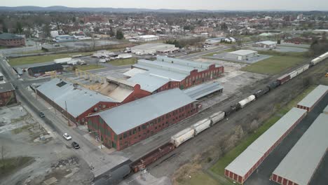 Aerial-drone-view-of-train-traveling-through-a-massive-industrial-facility