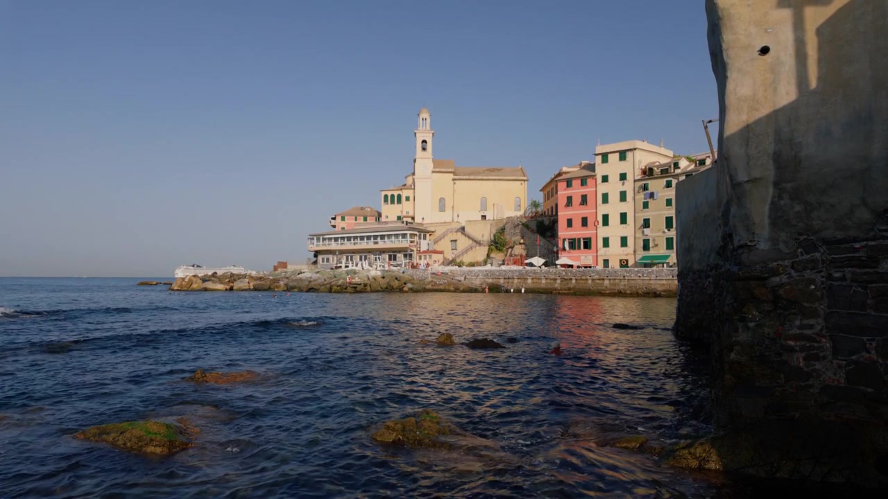 Case colorate di pescatori e chiesa si affacciano su una costa rocciosa in pieno giorno