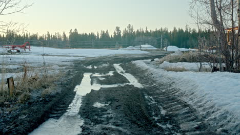 frozen muddy dirt road leading to farm entrance at sunrise