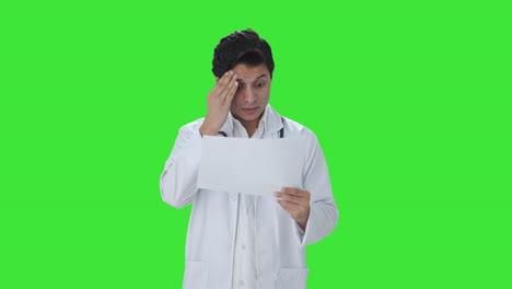 stressed indian doctor checking medical reports green screen