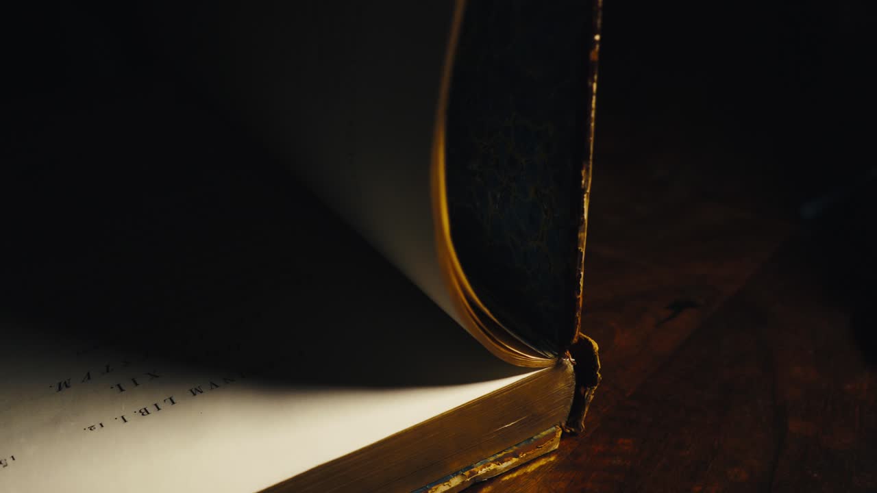 Close-up of an old book, which the person opens and turns its pages, reveals text written in Latin and an inner cover with blue marbling.