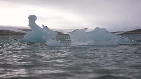 Cámara-Lenta,-Olas-Frías-Del-Mar-Alrededor-De-Trozos-De-Hielo-Flotando-Bajo-El-Glaciar