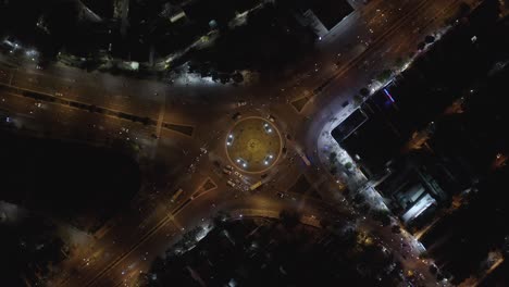 an aerial drone shot of rush hour traffic at roundabout intersection at night - descending