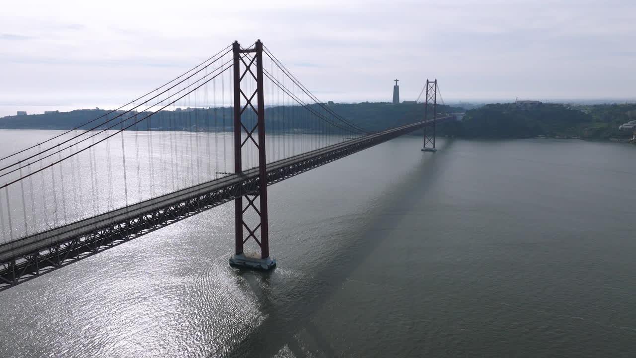 Beautiful aerial drone shot of the iconic red 25th April suspension bridge standing empty before the long-distance running event in Lisbon, Portugal, overlooking the Tagus river panorama