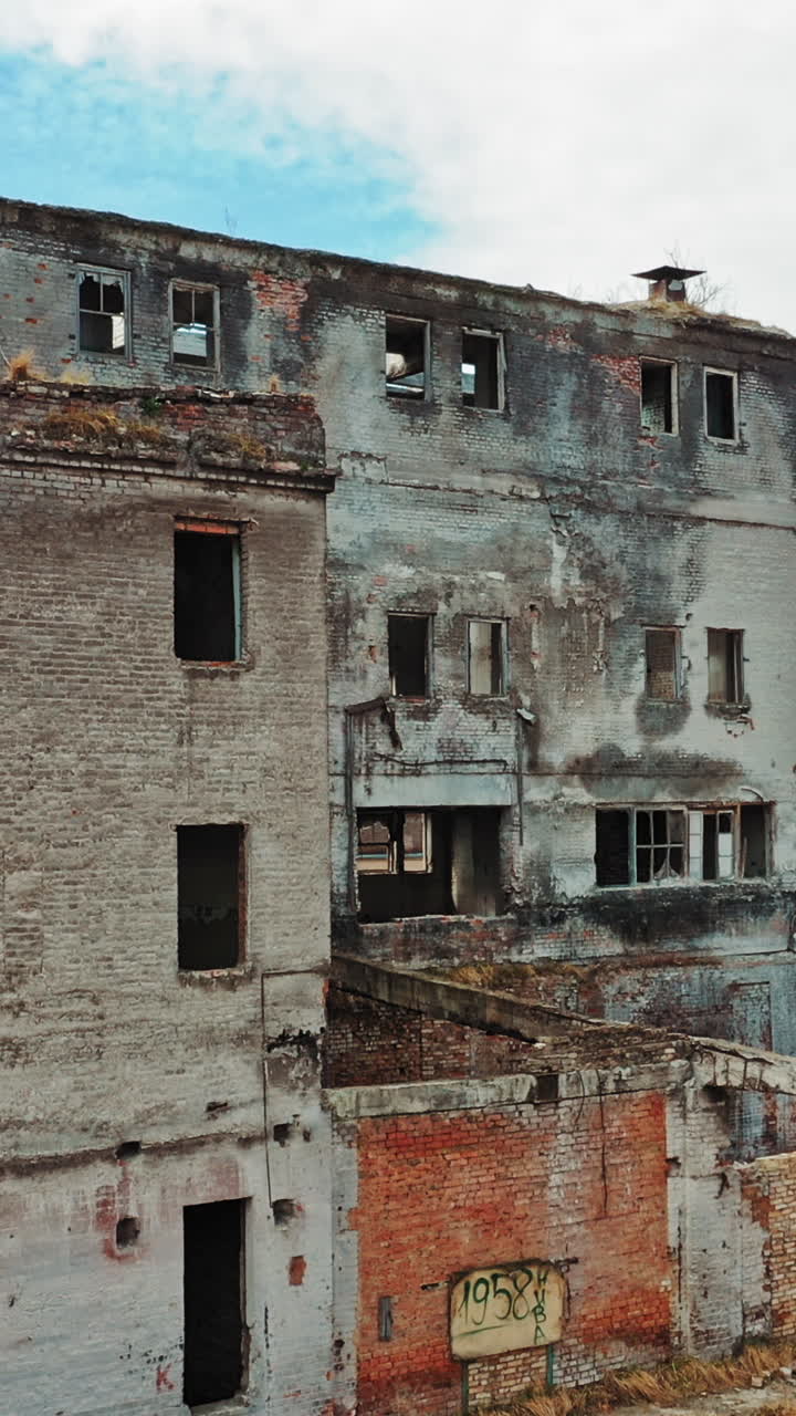 Abandoned building. Aerial view of an old factory ruin and broken windows. Vertical video