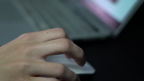 close up of hand scrolling, clicking a white computer mouse on dark background