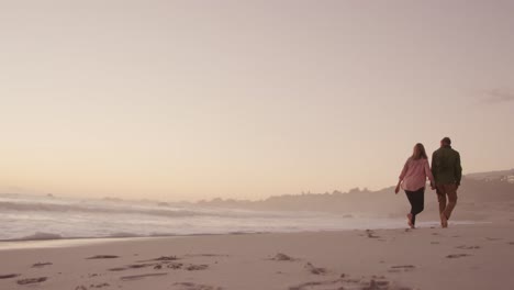 active senior couple walking on beach