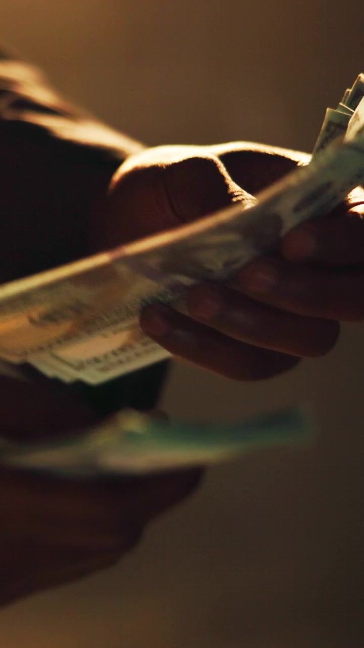 Person der tæller en bunke amerikanske dollarsedler