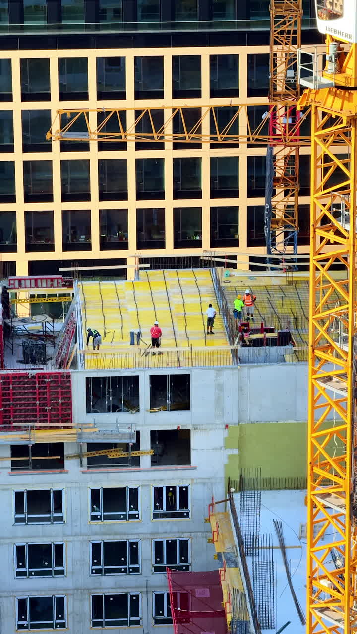 Workers build city structure. Construction workers are actively working on the rooftop of a building under development in a bustling urban area