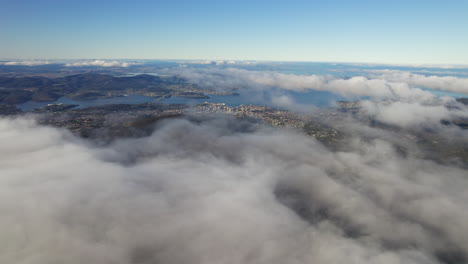 a drone shot of a city below clouds