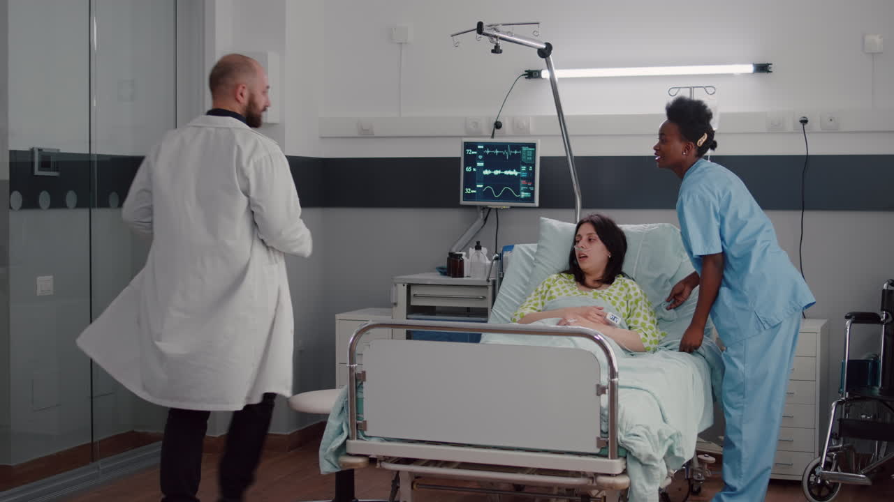 asistente negro ayudando al paciente a sentarse cómodamente en la sala del hospital