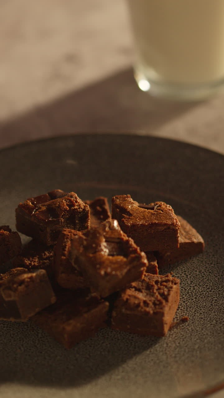 Vertical Video Of Person Picking Up And Eating Chocolate Brownies From Plate