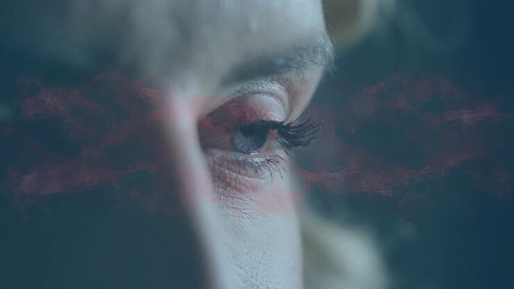 Donna che sbatte le palpebre, luce arancione che entra, produce una foschia rossa, bagliore e restringimento della palpebra per la tecnologia.