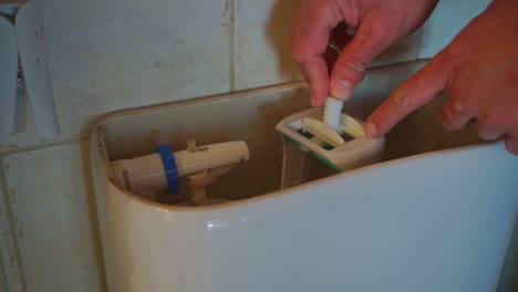 imágenes de primer plano de un hombre caucásico reparando una válvula de descarga del inodoro