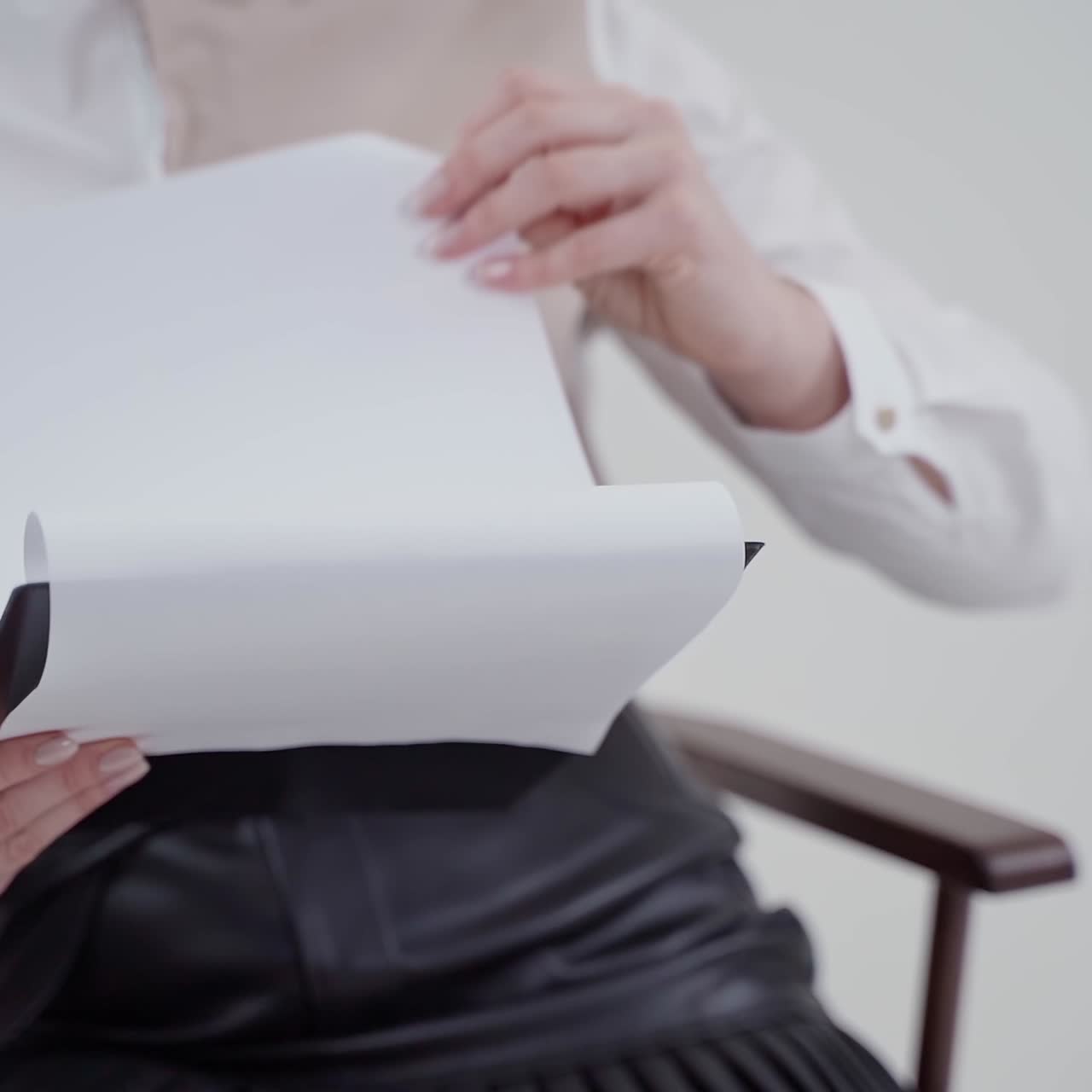Folder with papers in woman's hands. Young businesswoman sitting in chair and holding documents. Close-up. Slow motion.
