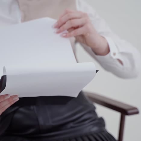 folder with papers in woman's hands. young businesswoman sitting in chair and holding documents. close-up. slow motion.