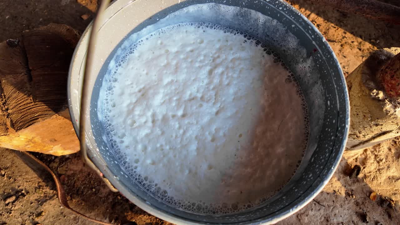 위에서 찍은 사진에서 갓 짜낸 신선한 우유로 가득 찬 양동이가 보이네요. 농장에서의 고된 하루 작업에 대한 소박한 보상을 기념하는 모습이에요