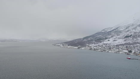 foggy scenery in kafjord with beautiful snowy mountains and calm sea views - aerial shot