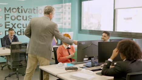 Boss delivering work folders to his employees in a office
