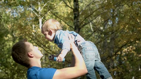 Dad tosses son into the air in an autumn Park. Happy family