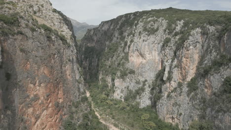 Drone-shot-near-Gjipe-beach-Albania-near-the-mountains-and-the-sea-on-a-sunny-and-bright-day-and-green-nature-around-in-between-rocks-gap-crack-massive-split-LOG