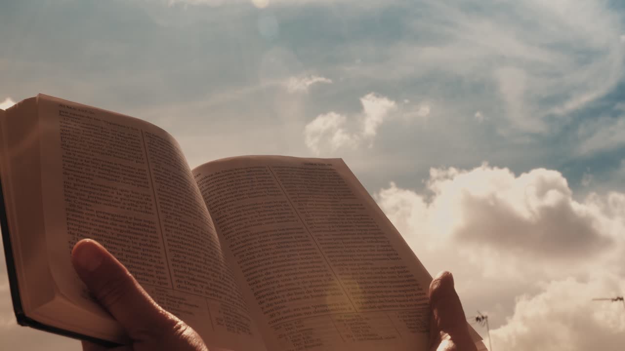Mani che tengono e aprono Il Libro di Mormon contro un cielo nuvoloso
