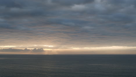 Toma-De-Lapso-De-Tiempo-Dramático-Del-Cielo-Oscuro-Moviéndose-Sobre-El-Mar-Mientras-Se-Forma-La-Línea-Del-Cielo-Dorado-Durante-El-Amanecer