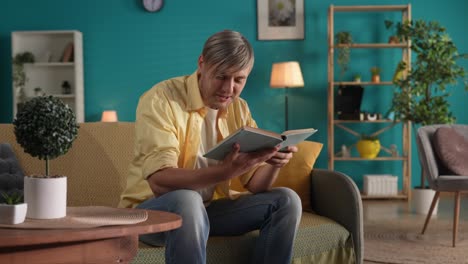 hombre leyendo un libro en un sofá