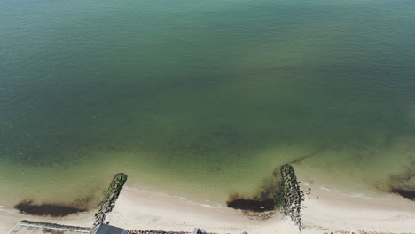 Panorámica-Aérea-De-Arriba-Hacia-Abajo-A-Través-De-Diques-Recogiendo-Algas-Y-Algas-Marinas-De-Las-Corrientes-De-Marea.