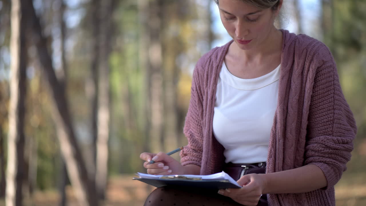 Woman sketching on a bench in the park on a sunny day