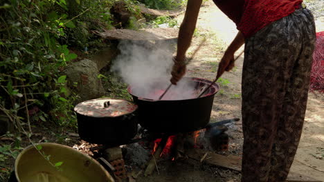 asian woman dyeing straws red in a large pot