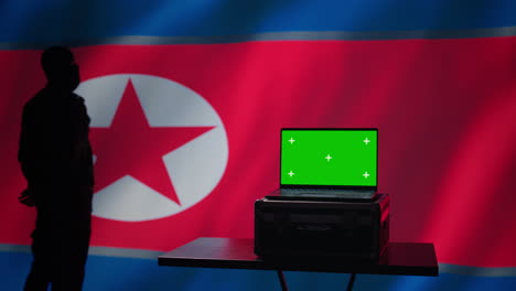 un agente de la policía secreta de corea del norte usa herramientas de propaganda en una computadora portátil de pantalla verde.