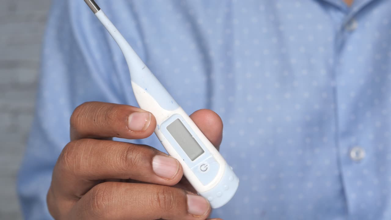 디지털 온도계를 들고 있는 사람