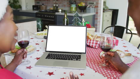 pareja afroamericana en sombreros de santa haciendo llamada de video de navidad portátil, con espacio de copia en la pantalla