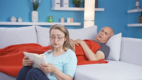 A-woman-reading-a-book-to-her-husband.-Happy-couple.