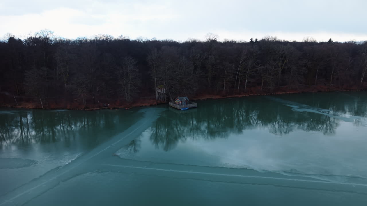 Aerial: Cabanes des Grands Reflets with wooden house on Verchat Pond during the day in Joncherey, France, orbit drone shot