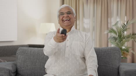 Happy-Indian-old-man-watching-TV-and-laughing