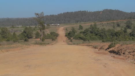 A-man-walks-on-a-lonely-dusty-dirt-road-in-Africa