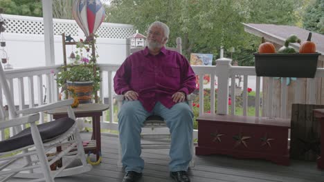 A-Senior-Male-Resting-in-a-Rocking-Chair,-on-a-Deck,-Enjoying-His-Retirement-on-a-Autumn-Day