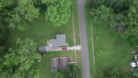 Aterrizaje-De-Drones-Aéreos-Sobre-Casas-Residenciales-Rodeadas-De-Exuberante-Vegetación-Al-Lado-De-Una-Carretera-Durante-El-Día