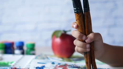 child holding paintbrushes