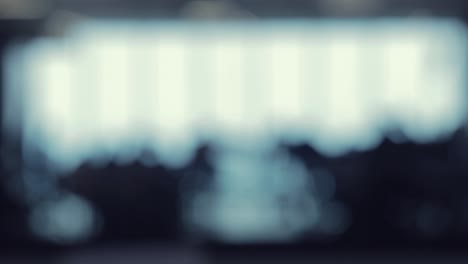 a defocused shot of many silhouettes of people walking around in a food court office building