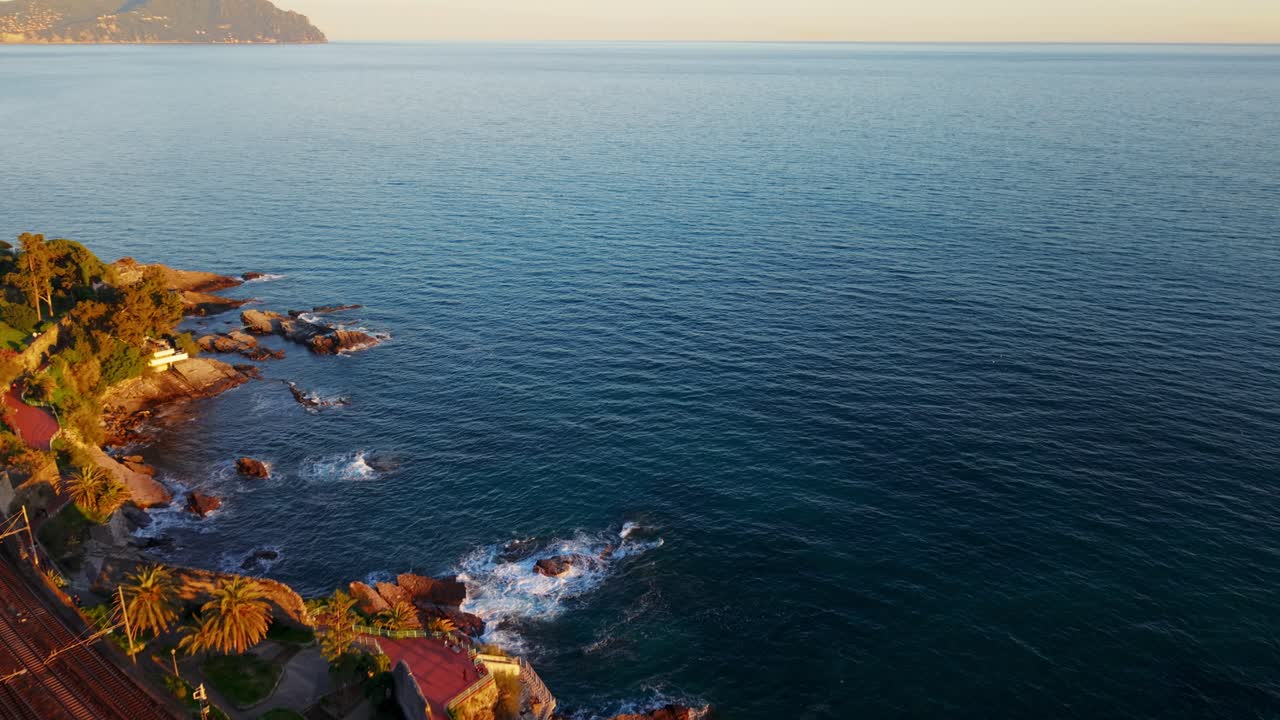The coastline in genoa, italy, with a railway along the beach at sunset, aerial view