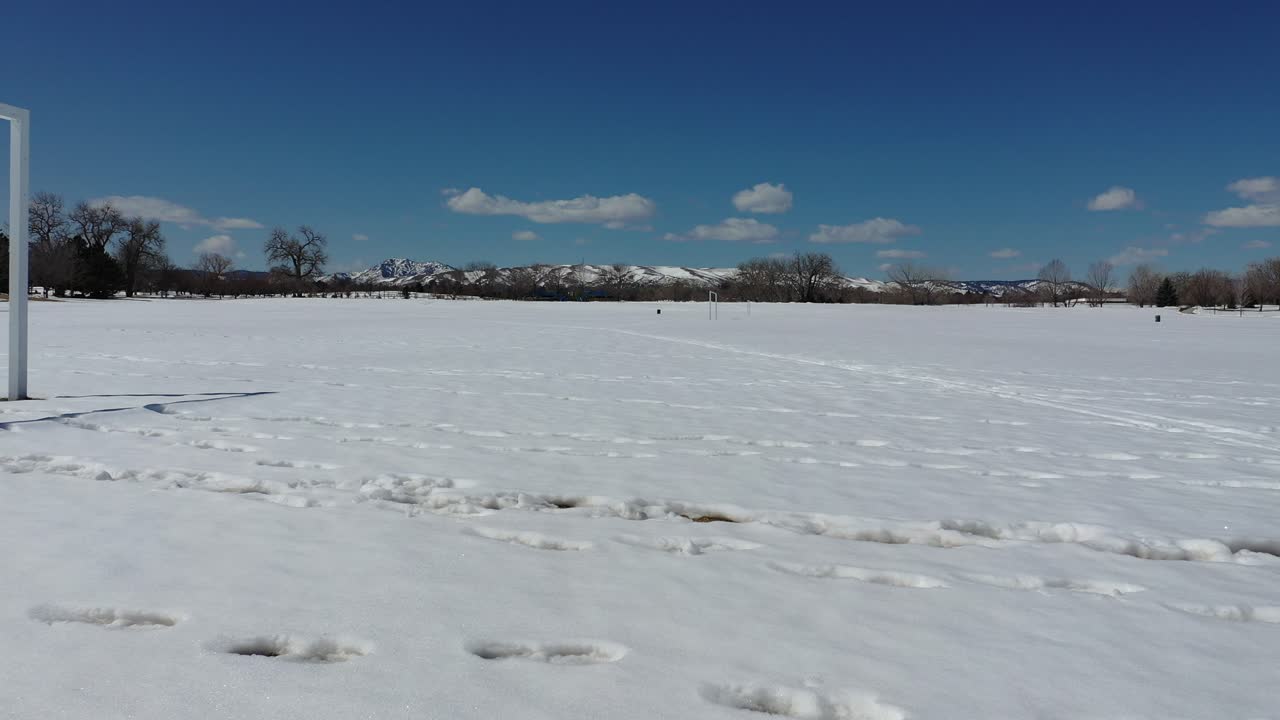 un dron corriendo disparó a través de un campo de fútbol vacío después de una nieve de primavera