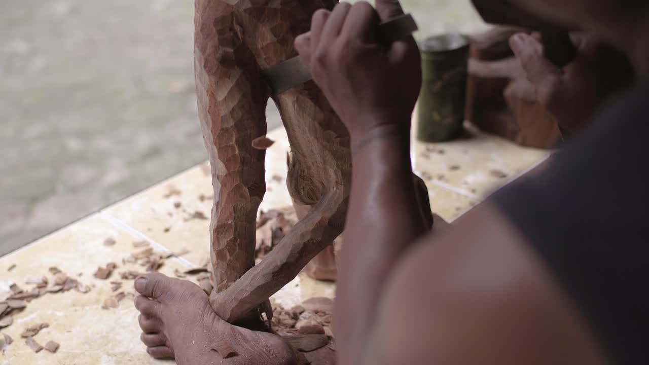 Homem fazendo uma estátua de madeira